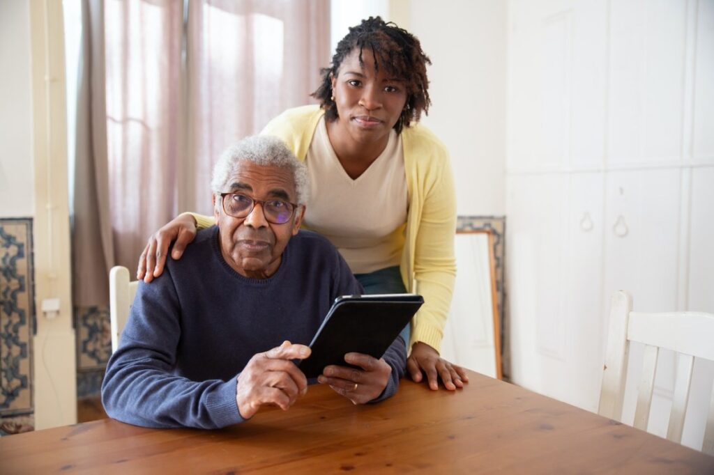 Seated senior man being helped by a home health assistant